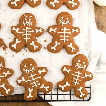 chocolate skeleton cookies are on a white parchment paper on a cooling rack